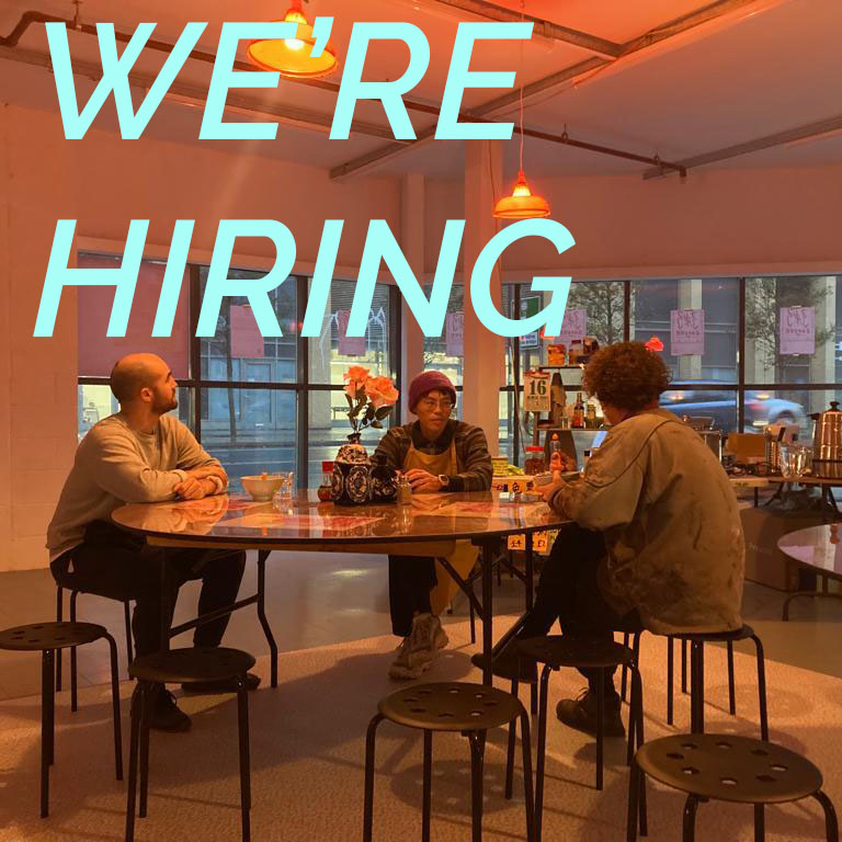 photo of three people sitting at a table Caption reads WE'RE HIRING